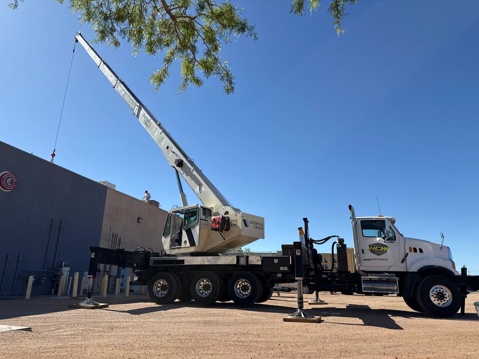 Boom truck on outriggers working over a commercial roof