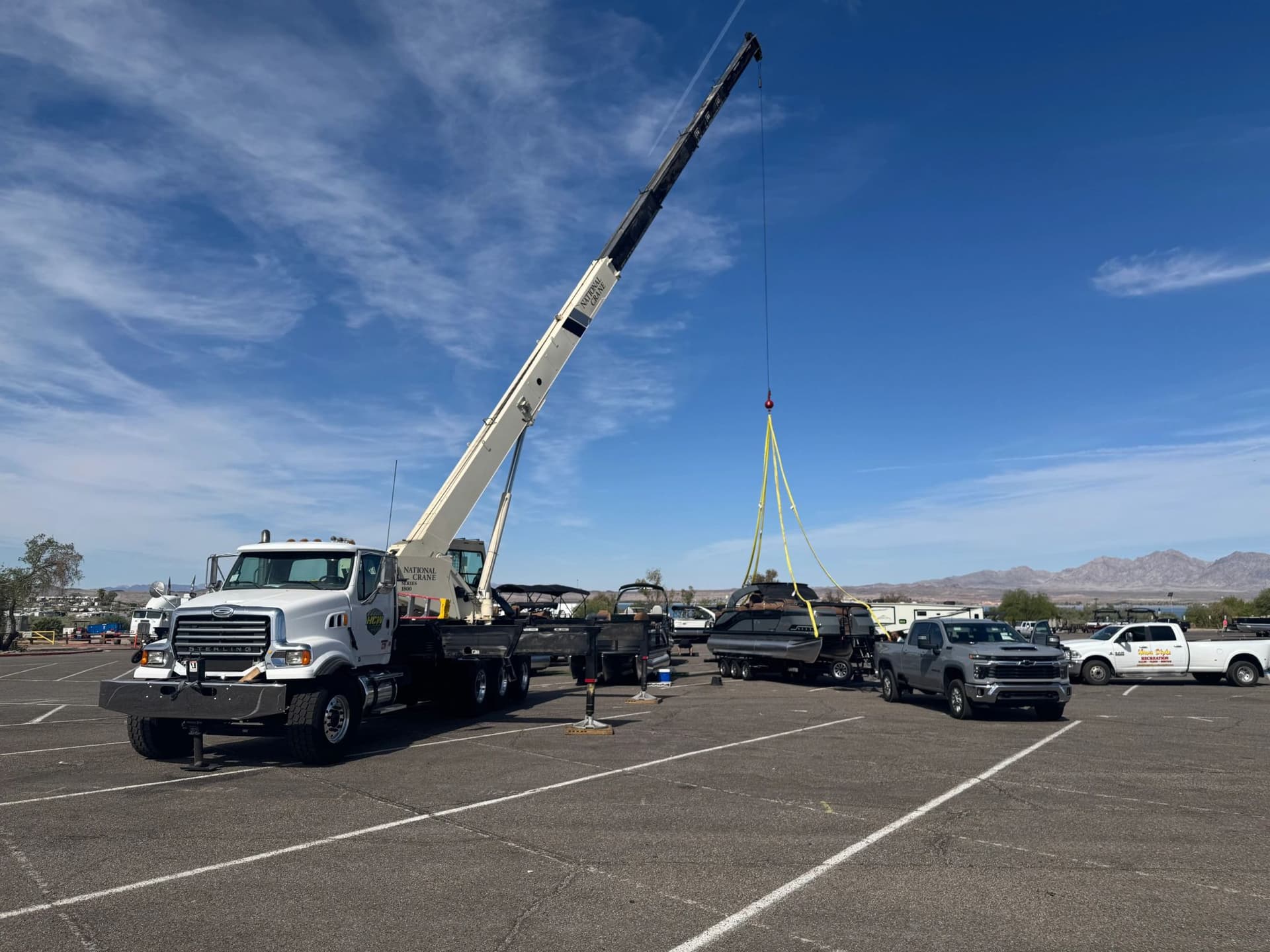 Boom truck rigging a boat beside the water