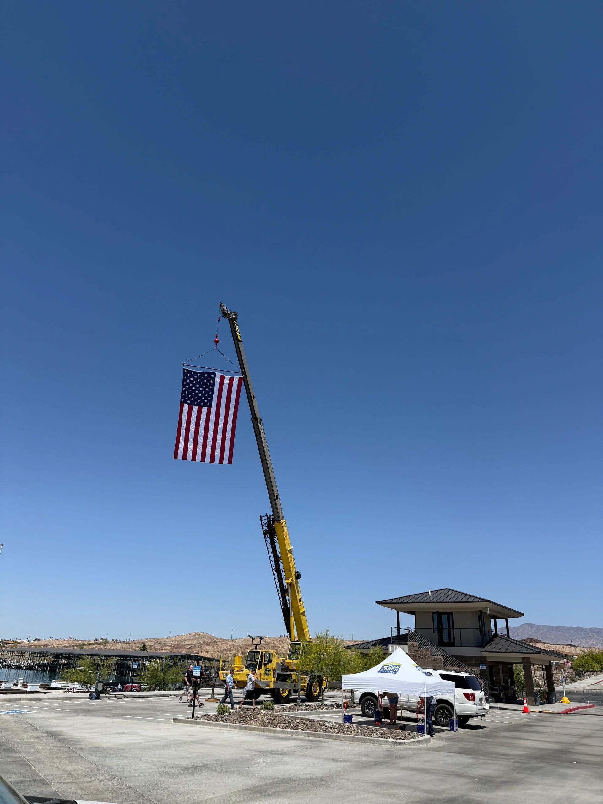 Rough-terrain crane flying a large American flag from its boom at a lakeside event